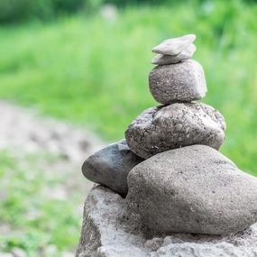 Mehrere Steine sind zu einem kleinen Turm in der Natur aufeinander gestapelt.